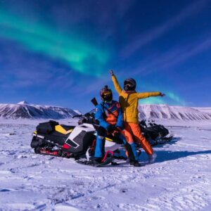 tourists on a snowmobile cheering in lapland