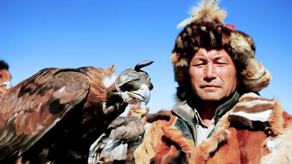 Man in traditional dress holding an eagle in mongolia