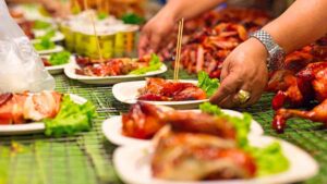 street food vendor in bangkok serving meat to tourists