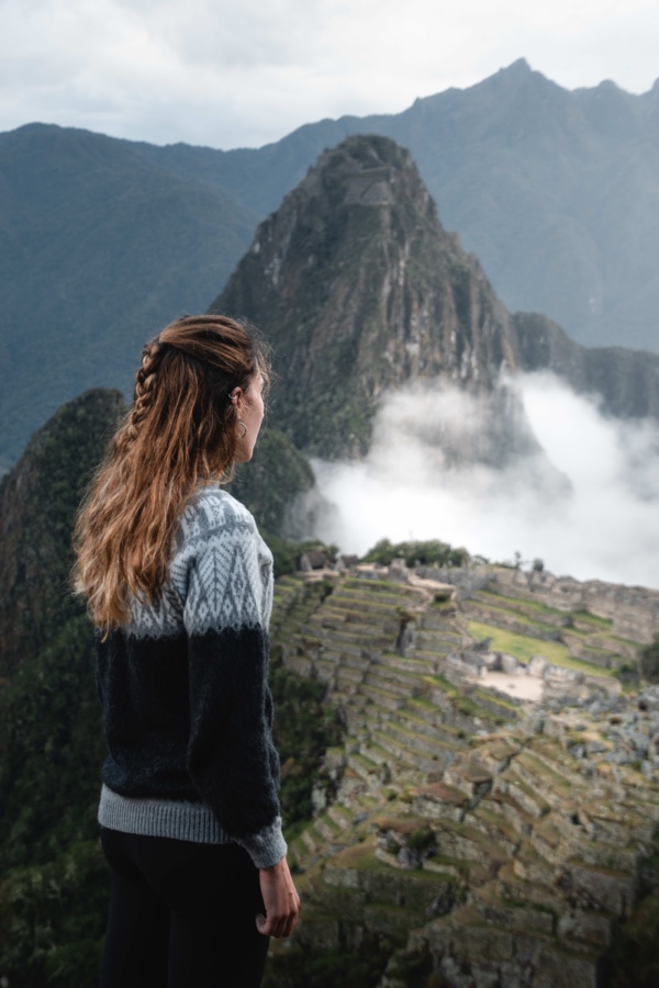 Female traveller admiring the ancient Inca citadel of Machu Picchu in Peru at sunrise